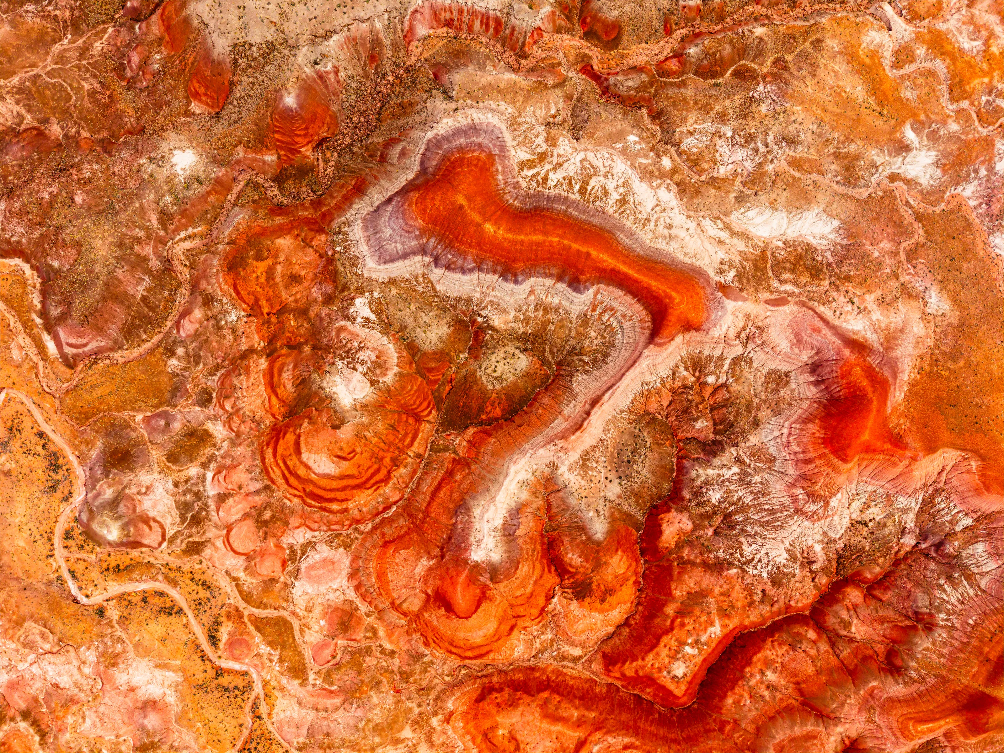 Aerial abstract of swirling red and cream bands of clay.